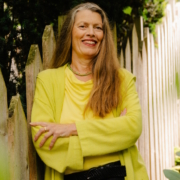 Jutta Heller steht mit freundlich lächelnd an einem Zaun