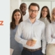 Ein vielfältiges, lächelndes Business-Team steht zusammen im Büro und zeigt Zuversicht beim gemeinsamen Umgang mit Multikrisen.